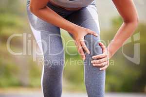 Active woman holding her leg in pain while exercising outdoors. Closeup of an athlete suffering with a painful knee injury, causing discomfort and strain. Muscle sprain from a fractured joint