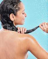 My hair is well taken care of. a young woman washing her hair in the shower against a blue background.