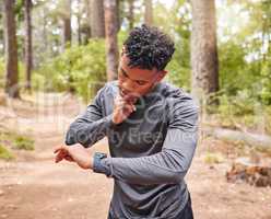 African American man checking his pulse while wearing a smartwatch and tracking his pulse, heartbeat and cardio health. Athlete using a device to keep track of his vitals while out jogging in a park