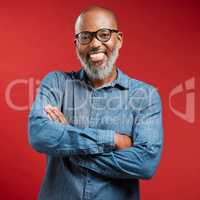Mature African American man wearing glasses and smiling while posing against a red background. Black male happy with his new spectacles frame at his optometry checkup. Improved vision makes him smile
