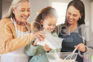 Baking makes the day sweeter. Shot of a little girl baking with her mother and grandmother at home.
