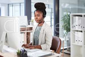 Running through a log of customer inquiries. a young call centre agent working on a computer in an office.