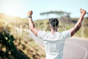 Rearview fit mixed race man celebrating a victory with his arms raised. Athletic male feeling overjoyed and cheerful after a win. Finding success with hardwork and dedication to health and fitness