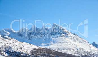 Landscape view of snow mountains and glacier ice after a heavy, arctic, winter snowstorm in Norway. Blue sky, copy space of vast mountainous landscape ideal for extreme sport in winter