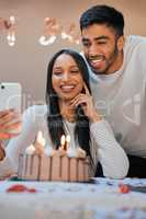 Capturing the special occasion. a young couple using a cellphone while celebrating a birthday at home.