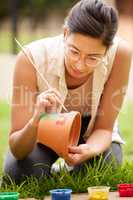 Creativity is seeing something that doesnt exist already. s young woman painting a pot in the garden at home.