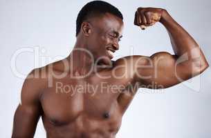 Buff and lovin it. a handsome young musclar man flexing in studio against a grey background.
