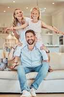 Portrait of excited little playful girl sitting on fathers shoulders and holding mothers hands while pretending to fly at home. Happy caucasian parents enjoying fun quality time with daughter