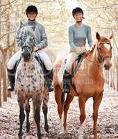 There is no better place. two attractive young women horse riding on a farm.