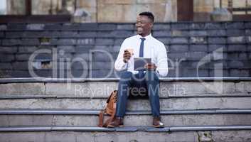 I belong in the city. a young businessman using a digital tablet in the city.