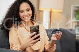 I dont need an excuse to spoil myself. Shot of a woman holding a credit card while using her cellphone.