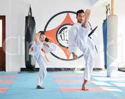 Dont let her size fool you. a young man and cute little girl practicing karate in a studio.