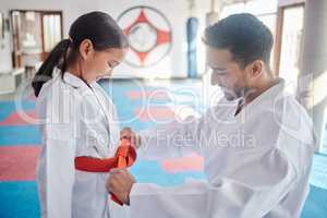 Its not too soon to learn a new skill. a young man and cute little girl practicing karate in a studio.