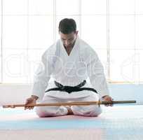 Picking up the mantel. Full length shot of a handsome young martial artist practicing bojutsu in his dojo.