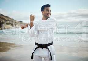 Its important for a fighter to properly prepare. a handsome young male martial artist practicing karate on the beach.