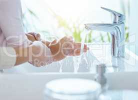 Wash all the germs away. an unrecognizable parent helping their child wash their hands at home.