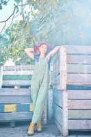 Portrait of a female farmer standing near crates on a fruit farm during harvest season. Farm worker standing in an orchard next to wooden storage containers and apple trees on bright sunny day