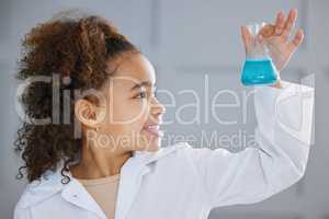 Observing the reaction. an adorable little girl wearing a labcoat while holding a beaker full of blue liquid.