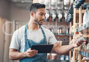 one young hispanic waiter using a digital tablet device while working in a store or cafe. Mixed race man checking inventory and stock of products while planning and browsing online