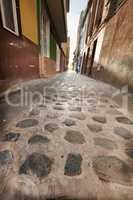 Stone alleyway road with scenic view of dark residential buildings, old historic houses with traditional infrastructure. Tourism abroad, overseas travel destination in Santa Cruz, La Palma, Spain