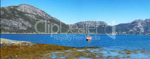 Wide angle landscape of a remote fishing lake near mountains. Stone hills by the nordic seaside with a bright blue sky. Calm water for a peaceful environment on a holiday in scenic Nordland nature