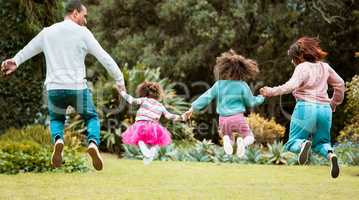 Jump for joy. Rearview shot of a young family holding hands while jumping outside.