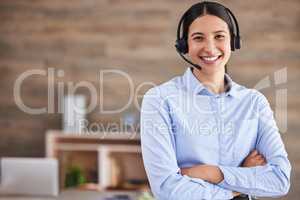 Young mixed race female call center agent standing with her arms crossed wearing a headset answering calls working in an office at work. Expert hispanic businesswoman customer service worker at work