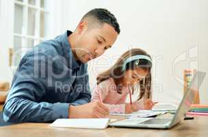 Working side by side with dad. an adorable little girl doing her homework next to her dad.