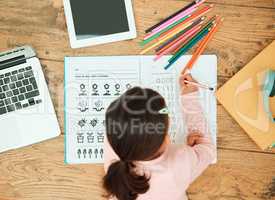 Doing her schooling at home. High angle shot of an unrecognizable little girl doing her homework.