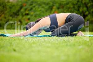 Bend over like you mean it. a young woman doing a downward yoga pose while exercising outdoors.