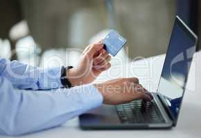 Closeup of one businessman spending money online with a credit card and laptop in an office. Making purchase transaction with secure banking payment. Budgeting finance for bills and ecommerce shopping