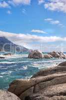 Landscape view of sea water, rocks and a blue sky with copy space in Camps Bay Beach, Cape Town, South Africa. Calm, serene, tranquil, ocean and relaxing nature scenery. Waves washing on rocky shore