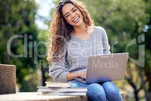 Doing some revision between classes. Cropped portrait of an attractive young female student using her laptop to study outside on campus.