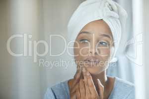 Its got to go. a young woman popping a pimple on her face at home.