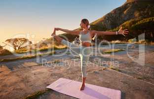 Full length yoga woman holding hand to toe pose in outdoor practice in remote nature. Beautiful caucasian person using mat, balancing while stretching alone at sunset. Young, active, zen and serene