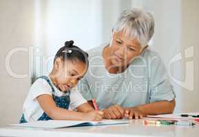 Those are beautiful colours. a grandma helping her granddaughter at the kitchen table at home.