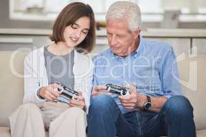 Patience and kindness. a mature man bonding with his grandchild while playing video games on the sofa at home.