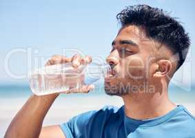 Nothing satisfies the thirst like water. a man drinking water while out for a run on the beach.