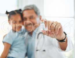 Just the cure she needed. a mature doctor holding a vaccine vial during a checkup with a little girl at home.