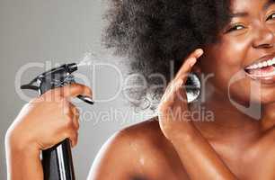 Spray it right on there. a young woman styling her hair against a grey background.