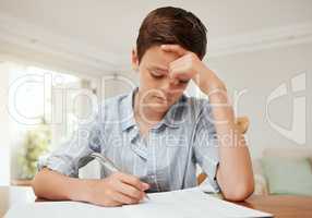 Felling blue. a young boy doing his homework at the kitchen table at home.