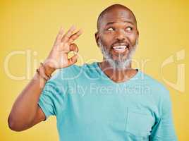 Mature african american man smiling while making an okay gesture with his hand against a yellow studio background. Expressing that everything is perfect. Showing support