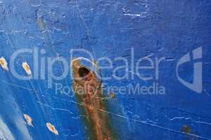 Abandoned and rusty limber hole on the side of docked ship outside. Closeup of rust stained hawsehole used for draining water on the hull of a nautical boat in a dockyard and port overseas and abroad