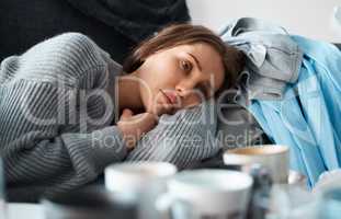 No motivation to do anything. Shot of a depressed young woman lying on her messy couch.