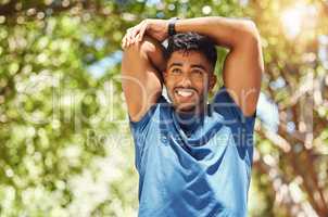 Fit athletic mixed race man smiling while stretching during a workout at the park. Young hispanic man doing warm up exercises outdoors on a sunny day. Dedicated to fitness and a healthy lifestyle