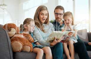 None of us were expecting that to happen. an attractive young woman sitting with her family on the sofa at home and reading a book.