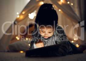 Sneaking in one more episode. a little girl using a digital tablet late at night at home.