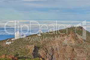 Roque de los Muchachos Observatory in La Palma. An astronomical observatory on a mountain top with blue sky copy space. Telescope surrounded by greenery and located on an island at the edge of cliff.