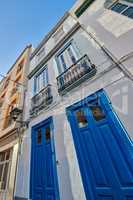 Classic architecture of vibrant buildings with blue doors in a city. Low angle of ancient and traditional homes or houses in a small vintage town or village with bright colors and a unique design