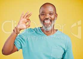 Mature african american man looking happy and smiling while making an okay gesture with his hand against a yellow studio background. Expressing that everything is perfect. Showing support